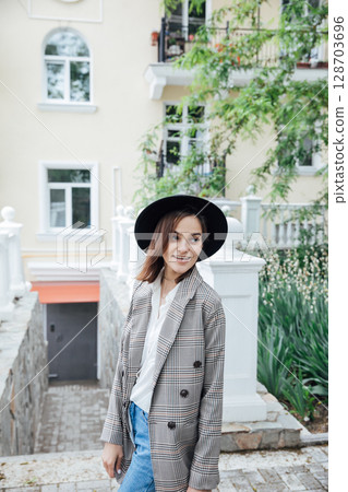 Beautiful fashionable brunette woman in a gray jacket walking along Beautiful fashionable brunette woman in a gray jacket walking along 128703696