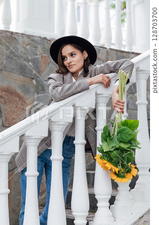 Beautiful fashion brunette woman wearing a hat with orange sunflowers Beautiful fashion brunette woman wearing a hat with orange sunflowers 128703700