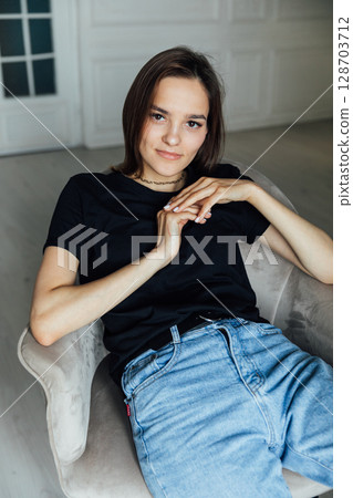 fashion brunette woman in jeans and t-shirt sitting on a chair fashion brunette woman in jeans and t-shirt sitting on a chair 128703712