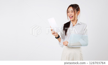Happy Asian woman with broken arm and bills after an accident, wearing sling arm brace, smiling for health insurance, recovery after life and accident injury, headshot isolated studio white background 128703764