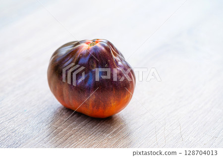 fresh picked multicolored striped and streaky black, purple, and red tomatoes on a wooden table fresh picked multicolored striped and streaky black, purple, and red tomatoes on a wooden table 128704013