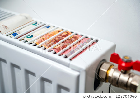 euro banknotes in a central heating radiator, the concept of expensive heating costs, closeup euro banknotes in a central heating radiator, the concept of expensive heating costs, closeup 128704060
