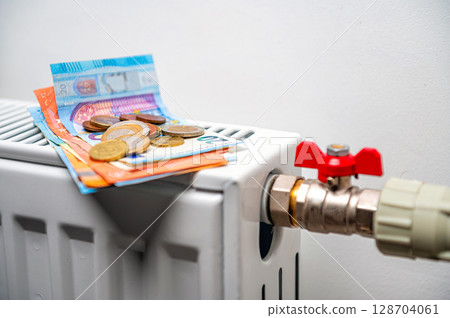 euro banknotes in a central heating radiator, the concept of expensive heating costs, closeup euro banknotes in a central heating radiator, the concept of expensive heating costs, closeup 128704061