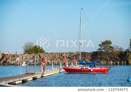 Yacht at a wooden platform in the port of Engure on the coast of the Baltic Sea 128704073