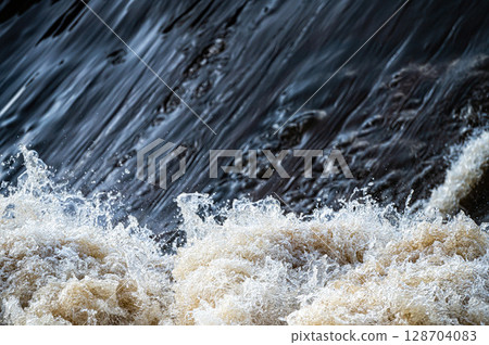 close up of flowing water, rapid water splashes of an white water river or stream, bubbly water close up of flowing water, rapid water splashes of an white water river or stream, bubbly water 128704083