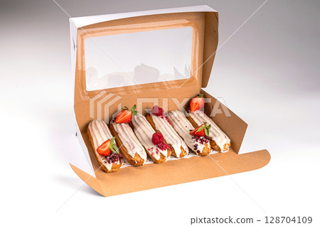 packing box with eclair with glaze and strawberries, isolated on white, closeup 128704109