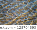 Transparent sea water and sandy bottom, ripples on the sea water, natural sea water background 128704693