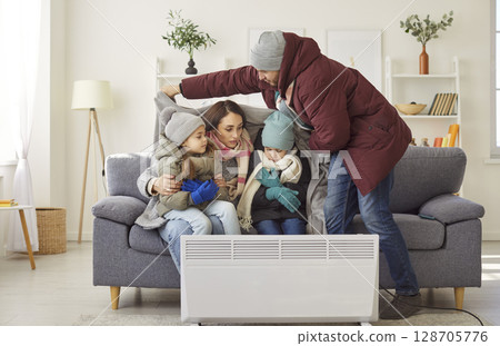 Freezing family trying to warm up near portable electric heater Freezing family trying to warm up near portable electric heater 128705776