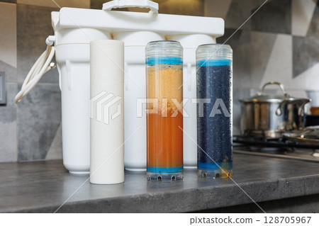 Replaceable cartridges in the water filter system. Water filtration system with replaceable cartridges. A system in the apartment with three tanks for cleaning tap water. Replaceable cartridges in the water filter system. Water filtration system with replaceable cartridges. A system in the apartment with three tanks for cleaning tap water. 128705967