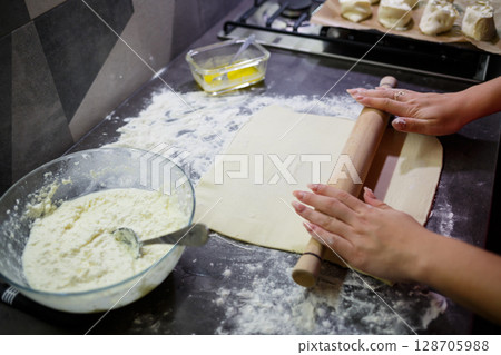 Baking domestic rolls with cheese. Putting cheese on dough for rolls Baking domestic rolls with cheese. Putting cheese on dough for rolls 128705988