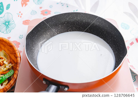 Heat milk and water in a saucepan 128706645