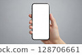 A hand holding a modern smartphone with a blank white screen against a neutral backdrop. 128706661