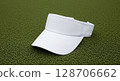 A white sun visor resting on a textured, green artificial surface. 128706662