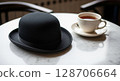 A black bowler hat sits on a marble table next to a cup of tea. 128706664