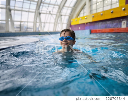 A smiling boy in the pool, a child in swimming glasses. An active child at the water park 128706844