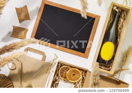 Eco friendly shopping and delivery service. Craft cardboard gift boxes, wooden box with bottle of champagne and empty blackboard on beige background. Zero Waste, plastic free, eco packaging concept 128708499
