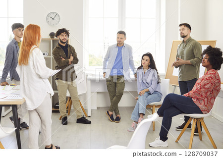 Group of business people chatting on a meeting standing in circle in office discussing work project. Group of business people chatting on a meeting standing in circle in office discussing work project. 128709037