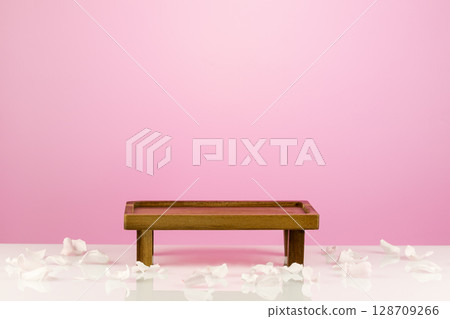 Wooden empty podium for food, products or cosmetics against pink gradient background with roses petals. Small decorative table for montage of product such as coffee and tea Wooden empty podium for food, products or cosmetics against pink gradient background with roses petals. Small decorative table for montage of product such as coffee and tea 128709266