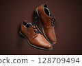 Elegant Brown Leather Dress Shoes with Laces on Brown Background 128709494