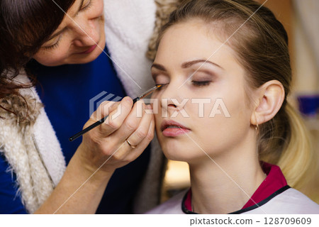 Woman getting eyes make up done by artist 128709609