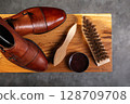 Elegant Leather Shoes with Shoe Care Accessories on Wooden Surface 128709708