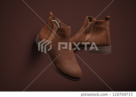 Stylish Brown Suede Chelsea Boots on Monochromatic Background 128709715