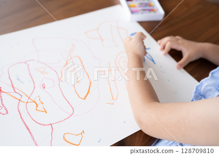 A close-up of an educational scene of a girl enjoying drawing with crayons A close-up of an educational scene of a girl enjoying drawing with crayons 128709810