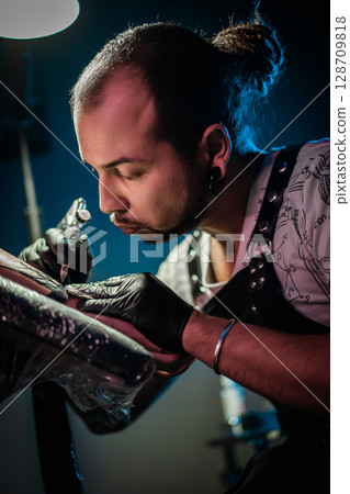 Man tattoo master with dreadlocks showing process creation tattoo, female body  128709818