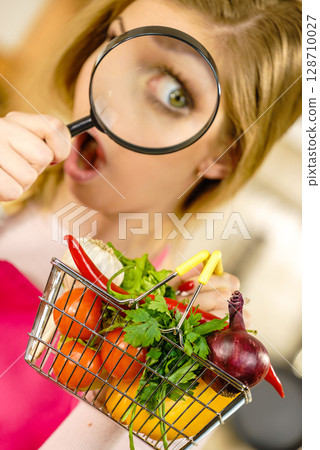 Woman investigating shopping backet with vegetables Woman investigating shopping backet with vegetables 128710027