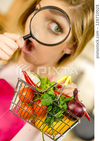 Woman investigating shopping backet with vegetables Woman investigating shopping backet with vegetables 128710028