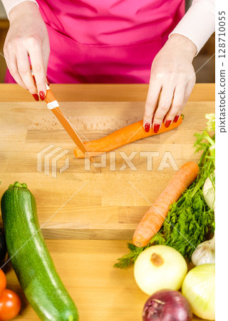 Woman cutting carrot on kitchen board Woman cutting carrot on kitchen board 128710055