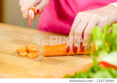 Woman cutting carrot on kitchen board 128710064