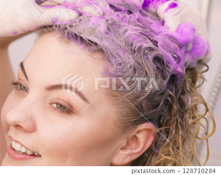 Woman applying toner shampoo on her hair 128710284