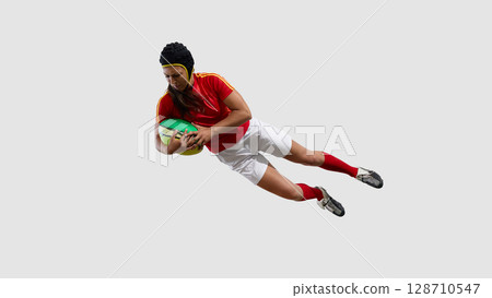 Female rugby player leaping with ball in mid-air action pose 128710547