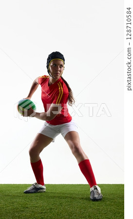 Female rugby player prepares to pass ball during practice on field 128710584