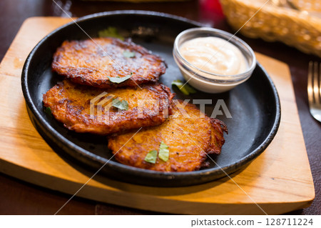 Potato pancakes with sour cream on frying pan 128711224