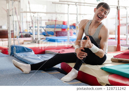 Injured male gymnast suffering from knee pain after bad landing 128711242
