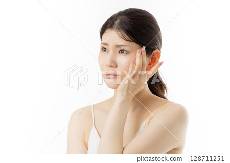 Facial expression of a young woman concerned about skin problems (white background) 128711251