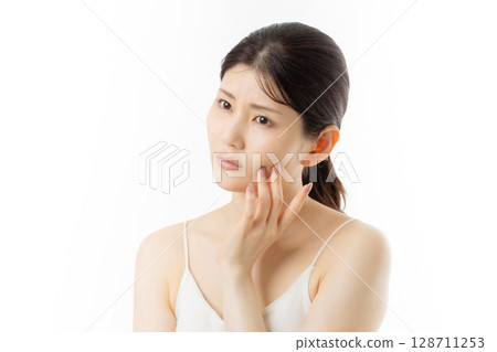 Facial expression of a young woman concerned about skin problems (white background) 128711253