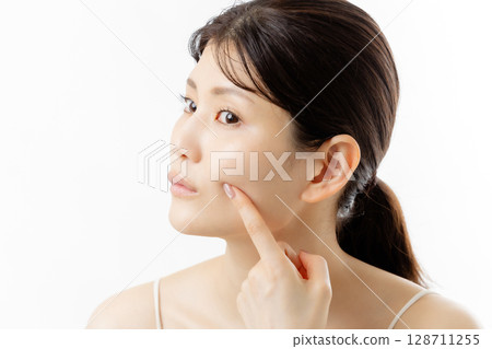 Facial expression of a young woman concerned about skin problems (white background) Facial expression of a young woman concerned about skin problems (white background) 128711255