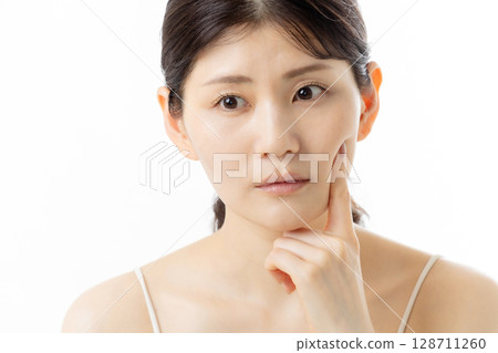Facial expression of a young woman concerned about skin problems (white background) 128711260