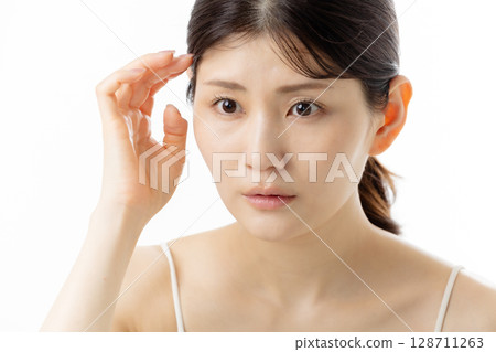 Facial expression of a young woman concerned about skin problems (white background) 128711263