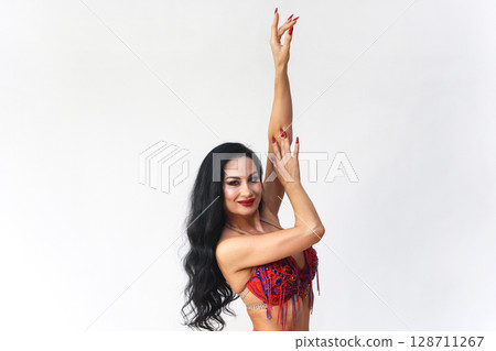 Brunette in Red Dress Performing Eastern Dance Movements Against a White Background Brunette in Red Dress Performing Eastern Dance Movements Against a White Background 128711267