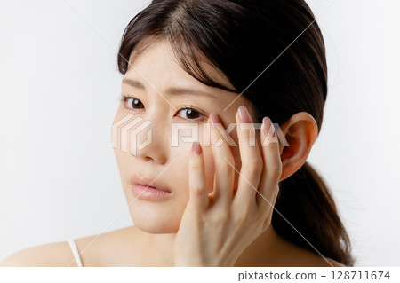 Young woman worried about eye problems (white background) 128711674