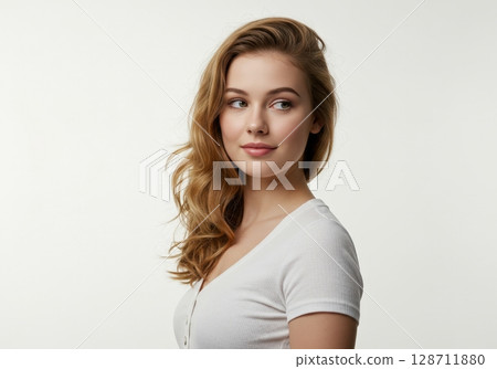 A beautiful young woman with long blonde hair and natural makeup smiling gently in a studio 128711880