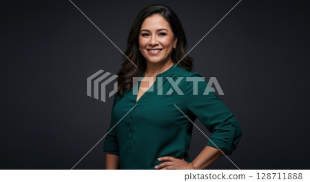 A confident mature hispanic woman in a green blouse smiling happily in a studio portrait 128711888