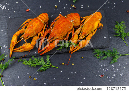 Red boiled crayfish with dill and spices on black slate background. Top view 128712375