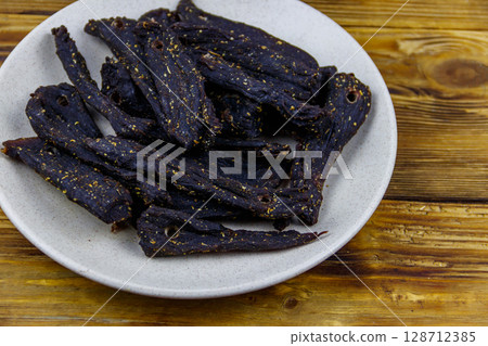 Slices of biltong (South African dried meat) on wooden table Slices of biltong (South African dried meat) on wooden table 128712385
