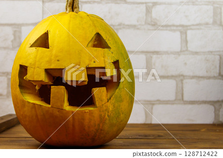 Spooky Halloween pumpkin jack-o-lantern on a wooden background Spooky Halloween pumpkin jack-o-lantern on a wooden background 128712422