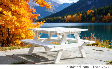 An autumn mountain landscape with a serene lake, a lone bench, and reflections of the scenic sky 128712877
